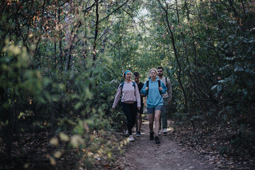 Happy hikers enjoy an autumn day off in the forest, exercising, exploring, and having fun conversations amidst natures beauty. A perfect weekend getaway with friends in a green, serene landscape.