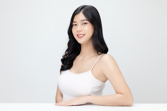A smiling Asian woman with fresh facial skin shows natural beauty and sensuality in a studio portrait.