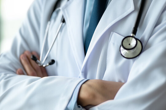 doctor's hands folded on his chest in a white coat with a statoscope around his neck