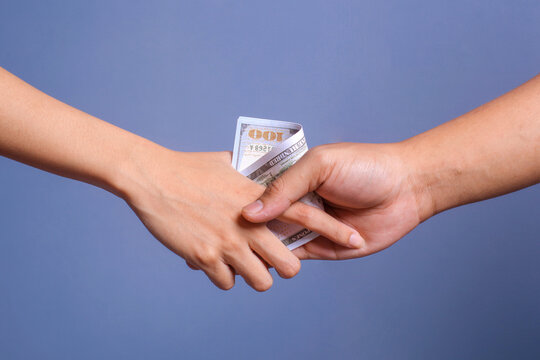 Businessmen hand shaking with money in hands isolated on blue background. Bribery, corruption and venality concepts