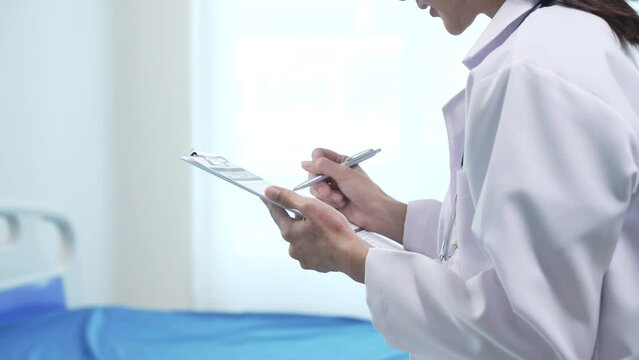 Asian people professional healthcare worker doctor, white coat, looking attentively at tablet in her hands. clinic or hospital with a bright and clean background.