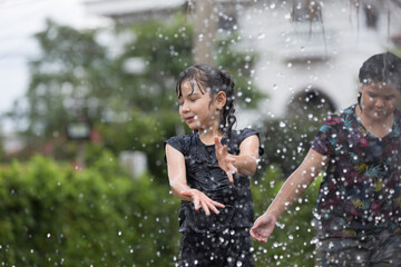 Cheerful little children girl playing during raining in rainy season