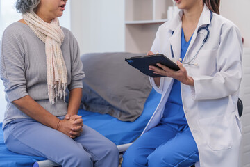 Health check concept, Elderly Asian woman with grey hair, sitting and talking to young Asian nurse by appointment, sitting on medical bed.