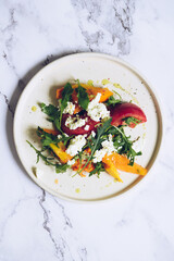 Healthy salad with different types of tomatoes, sweet potato, feta cheese and arugula