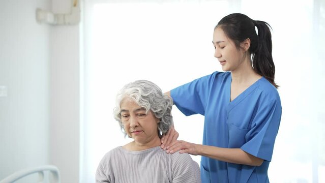 Physiotherapist doing physical therapy to an elderly Asian woman examining the treatment of a female patient's injured arm to rehabilitate the painful arm with a female doctor Health care concept