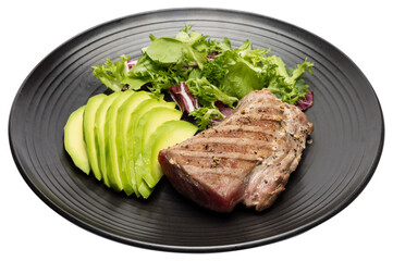 grilled cooked piece of tuna fillet with sliced avocado and salad on black ceramic plate