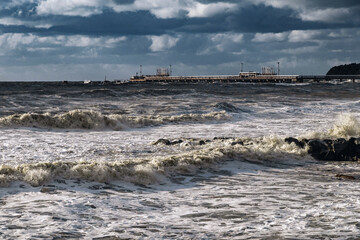 Large waves crash against the shore under an impressive cloudy sky. Beautiful sea waves beat against the shore during a storm. A storm on the Black Sea coast. A view of the epic stormy seascape. 