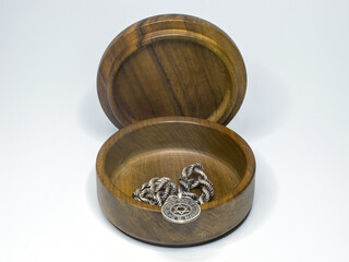  A silver chain with a Magen David medallion lies in a round walnut box with an open lid. Isolate on white.