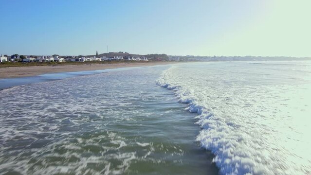 Low drone flight over waves rolling on to long stretch of Paternoster beach