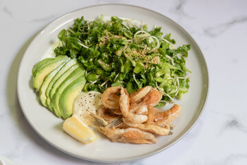 Green salad and avocado with fried toro salmon. Healthy and balanced menu.