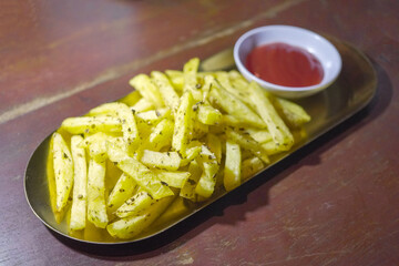 French fries and chili sauce on a wooden table background