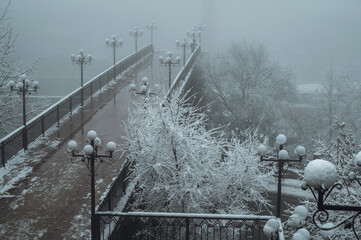 beautiful mystical winter landscape on a bridge with lanterns in a city with snow and fog