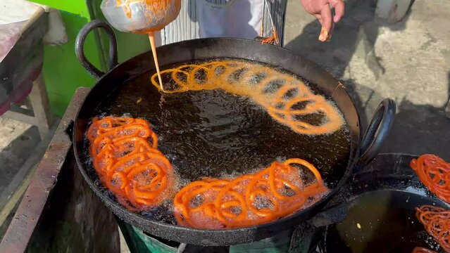 Jalebi is a popular sweet snack in South Asia. Making traditional sweet orange jalebi snacks in Pakistan street food market.