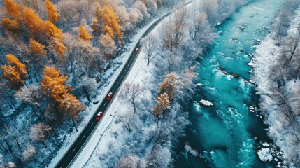Aerial top view of winter snowy road with red cars over blue river.