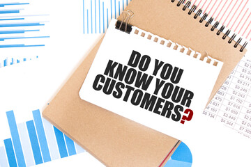 Text DO YOU KNOW YOUR CUSTOMERS on white paper sheet and brown paper notepad on the table with...