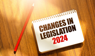 CHANGES IN LEGISLATION 2024 on notebook with red pencil on wooden background