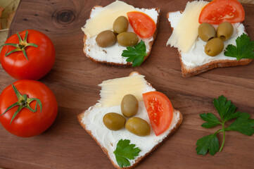 Sandwich with green olives and tomato on a wooden cutting board. Top view. Food concept.