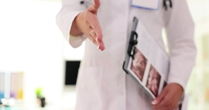 Doctor with documents extending hand for handshake in clinic closeup 4k movie slow motion