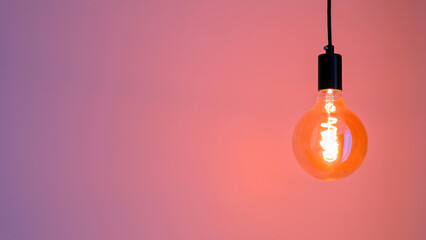 Retro Edison lamp on a pink-violet background. Space for text. Copyspace.