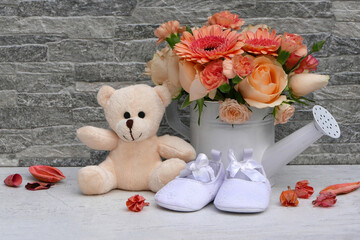 Ein Strauß Blumen mit Teddybär und Babyschuhe
n.