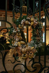 Christmas and New Year street decoration, round Christmas wreath hanging on metal gates, illuminated glass door at night, Epernay, Champagne, France