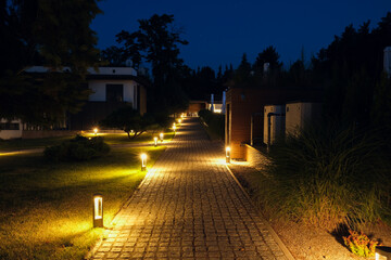 Alley, stone path in a country residence illuminated by street lamps.