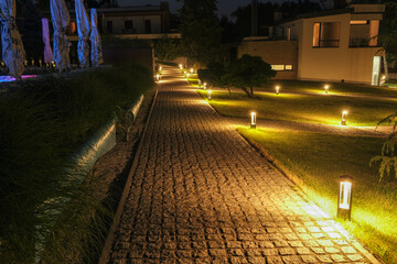 Alley, stone path in a country residence illuminated by street lamps.
