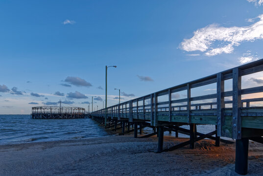 The setting suns Orange light falling on the sand beneath the Pier at Palacios on the Gulf Coast of Texas close to the City of Rockport.