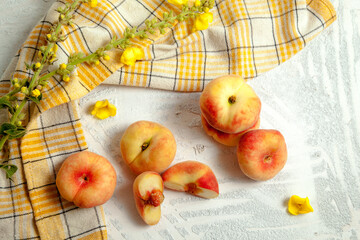 Halves and several whole saturn peaches or flat peach on white wooden background.. © kostik2photo