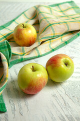 Three green apples on white wooden background..