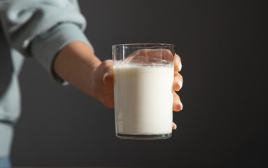 Hand holding a glass of milk on the table.