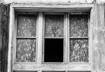 old wooden window, with one missing  piece of glass. Black space. Window frame, black and white , Monochrome. Part of the old abandoned house.  