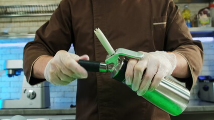 Chef screws in and locks in new carbon dioxide charger. Man uses whipping siphon for further...