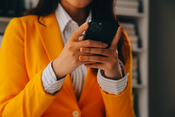 Business woman using mobile phone during working on laptop computer, surfing the internet, searching business data at modern office. Asian businesswoman online working on computer at workplace
