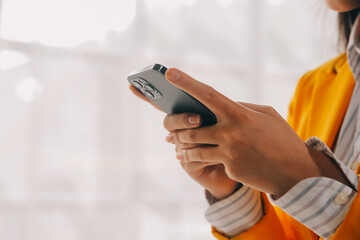 Business woman using mobile phone during working on laptop computer, surfing the internet, searching business data at modern office. Asian businesswoman online working on computer at workplace