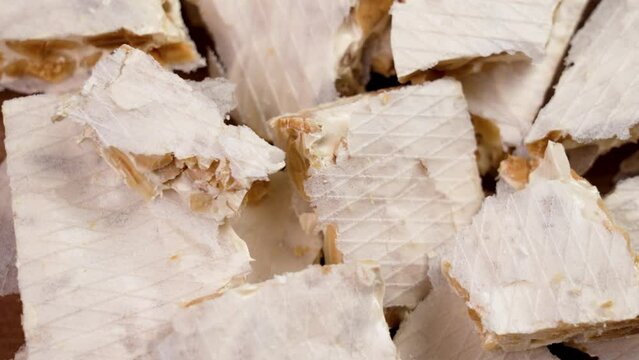 Traditional Spanish christmas hard Turron with broken pieces of nutty nougat and almonds close up. Rotation