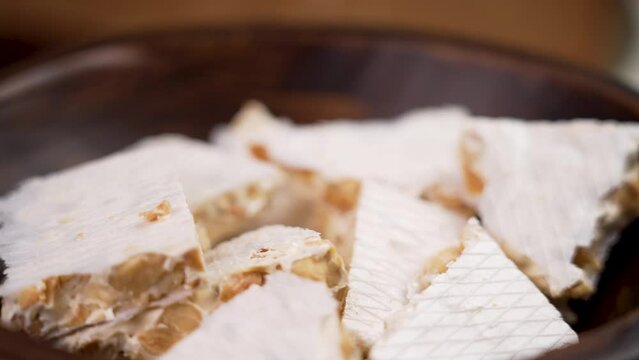 A hand takes a piece of hard typical Spanish almond turron. European delicious nutty nougat