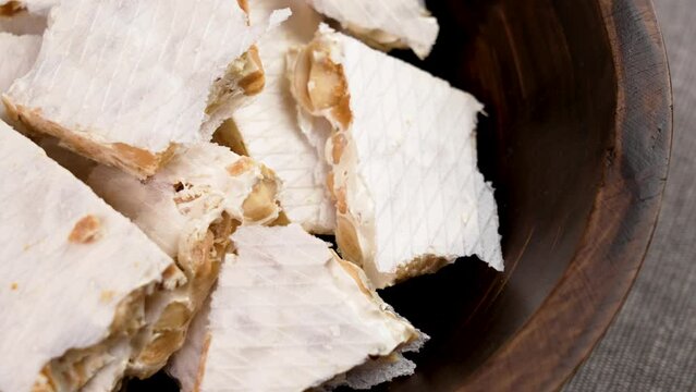 Pieces of traditional hard Spanish Turron in wooden rustic bowl. Typical festive dessert in Spain. Rotation
