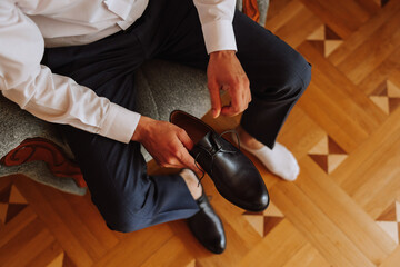An elegant man wears black leather formal shoes. Tying shoes. Business man tying shoelaces on the...