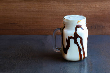 a glass of coffee and vanilla lata milkshake on a wooden background - obrazy, fototapety, plakaty