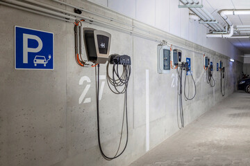 Charging Station for Electric Car EV in Underground Car Parking Garage in Multifamily Building. Electric Vehicle Charger Panel Station for Electro Cars. Home Power Charger. - obrazy, fototapety, plakaty