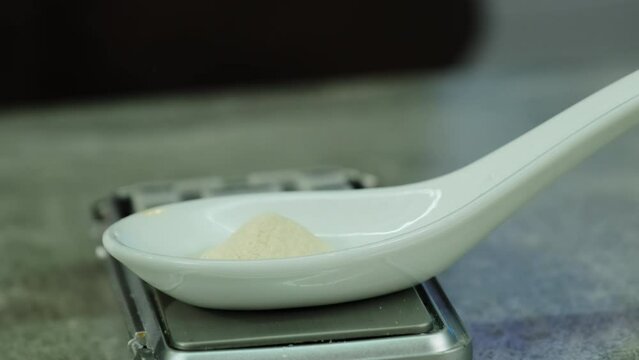 Chef with expertise in molecular cuisine measures required amount of agar-agar by sprinkling into measuring spoon. Process of jelly making