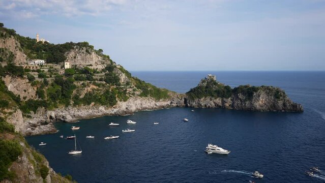 Scenic view from rock on yachts and boats docked near rocky headland with Torre del capo di Conca. Ship sailing in Mediterranean sea on background of beautiful seascape and mountain on summer day.