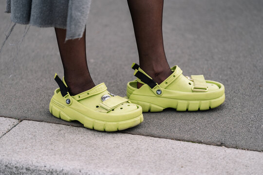 Milan, Italy - February 23, 2023: woman wearing crocs classic clog Sankuanz lime punch. Fashion blogger outfit details, street style