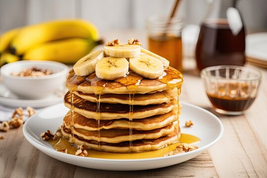 Healthy breakfast of oatmeal banana pancakes topped with fresh bananas walnuts honey and a cup of tea on a white wooden background Copy space