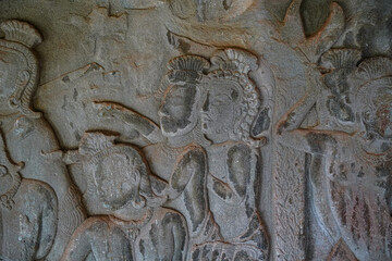 Ancient asian stone wall carving of humans in temple in Cambodia Angkor Wat Siem Reap vertical
