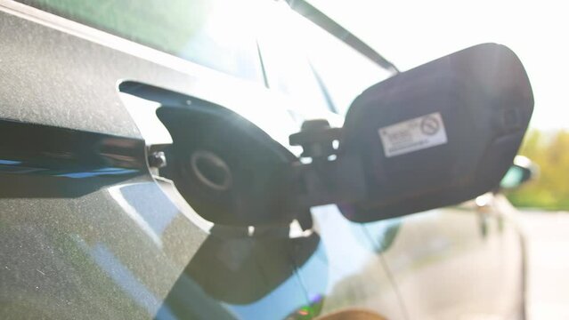 a man takes out a fuel pistol from a car's gas tank after refueling against the background of the sun, industry. Slow motion