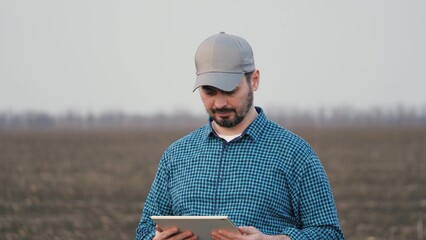 Male farmer is working in field with digital computer looking at camera smiling. An agronomist with...