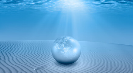 A large pearl shaped Earth lies on the sand dune -  Blue sea or ocean water surface and underwater with sunny day  