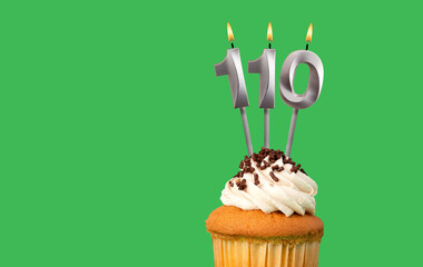 Birthday with number 110 candle and cupcake - Anniversary card on green color background